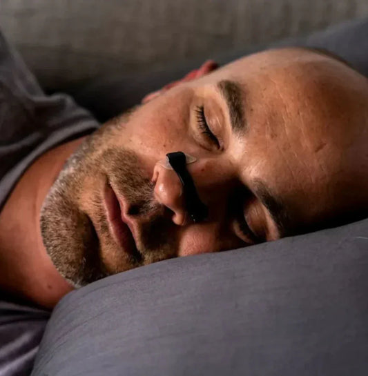 man sleeping with black magnetic nasal strips for snoring